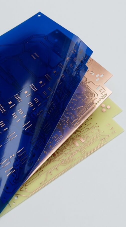 pcb impreso apiladas con película protectora azul mostrando pistas y perforaciones